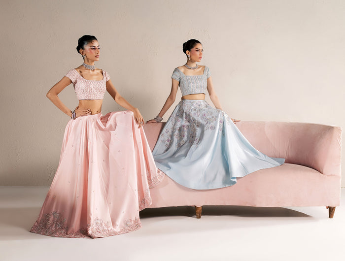 Eraya Seréne blush pink and ice blue lehnga choli sets with floral embellished hems, on a pink velvet sofa